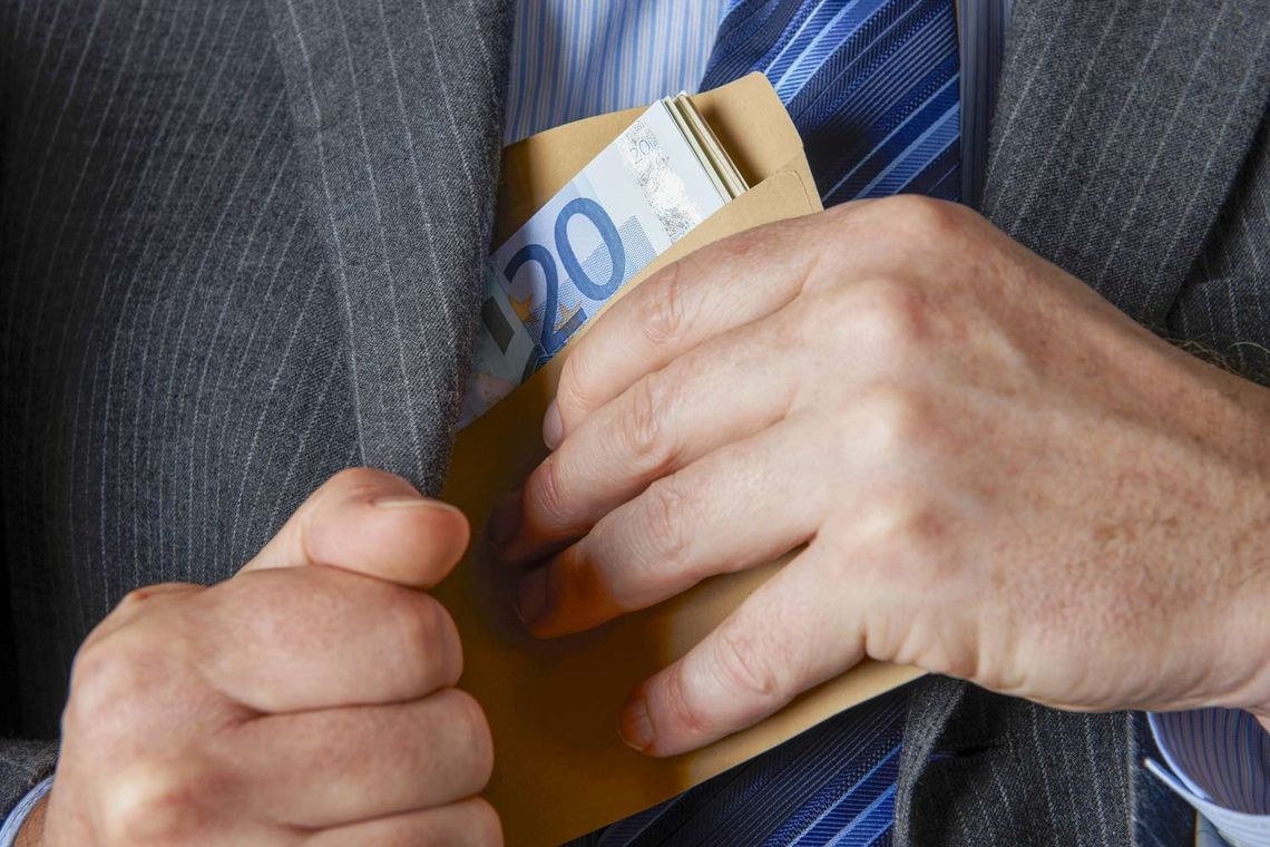 Foto von einem Mann, der Geldscheine in seinen Anzug steckt